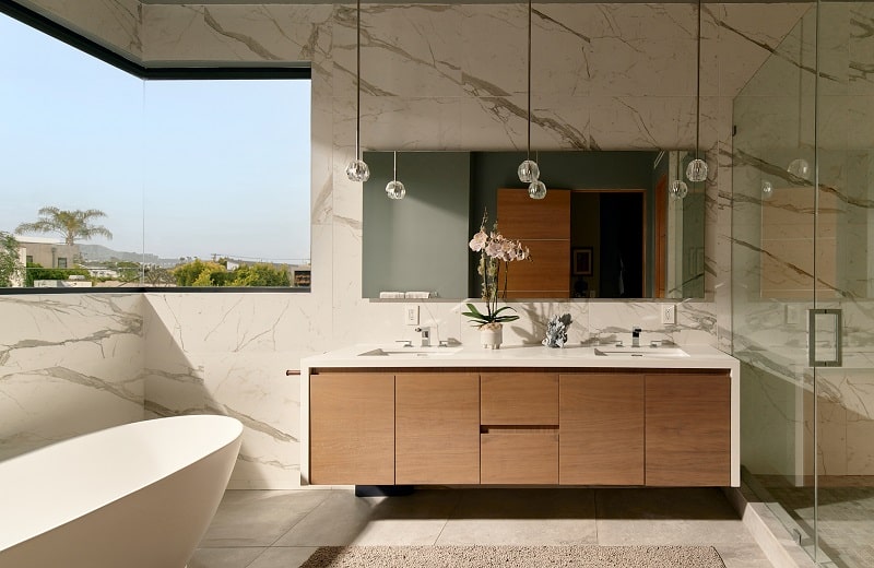 sleek modern bathroom with double wood vanity, plastered in white quartz with marbling 