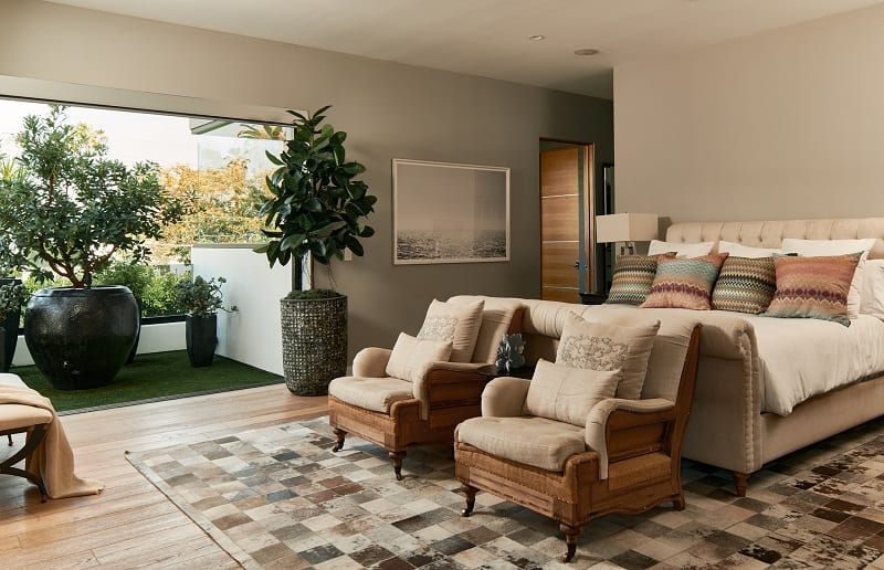 bedroom with bed, two armchairs and large windows that open to outdoor area