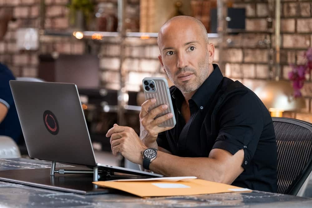 Jason Oppenheim speaking on the phone while sitting in front of his laptop in season 6 of Selling Sunset.