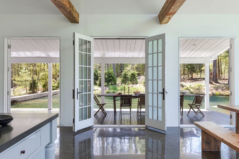 Doors opening to the outdoor areas, with the water and forest in the background