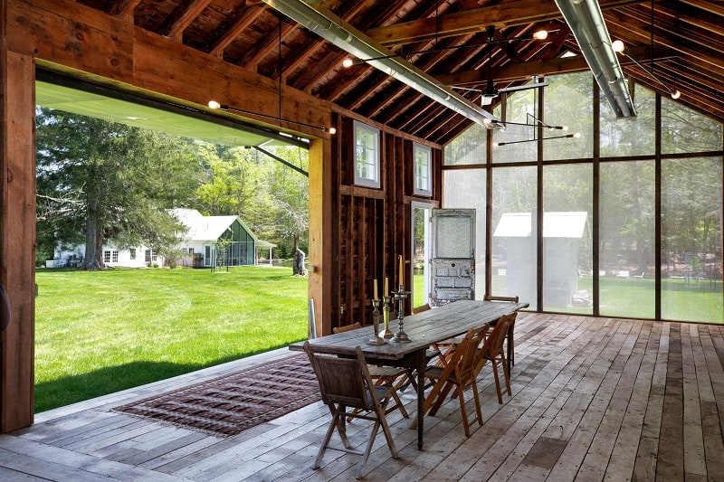 century-old wood barn with picture windows and a dining table