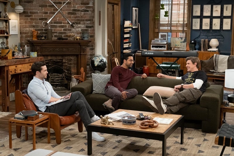 Charlie (Tom Ainsley), Sid (Suraj Sharma), and Jesse (Christopher Lowell) lounging and smiling inside the HIMYF apartment. 