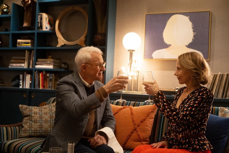 Charles' apartment in Only Murders in the Building, anchored by a smartly striped Paul Smith fabric which inspired the rest of the interior design. Charles (Steve Martin) and Jan (Amy Ryan), shown knocking wine glasses. 