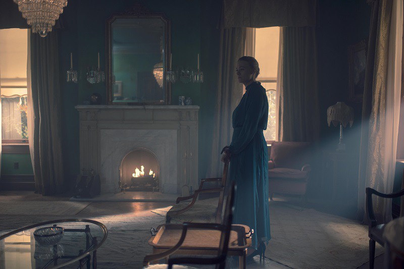 Serena inside the Waterford house, The Handmaid's Tale, with a lit fireplace in the background.