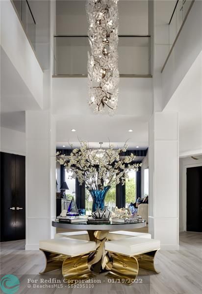 the entrance to Leo Messi's house has 27-foot high ceilings, a hanging chandelier with crystals, and a designed table