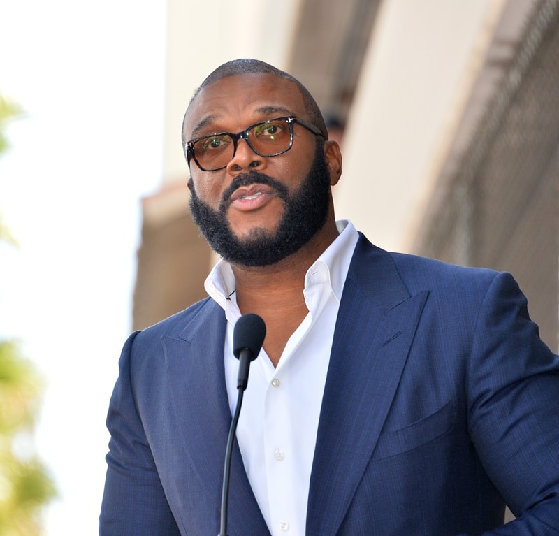 Tyler Perry speaking at an event, wearing a dark blue blazer