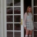 Alicia Silverstone as Cher Horowitz standing at the entrance of her Clueless mansion. Photo credit: IMDB