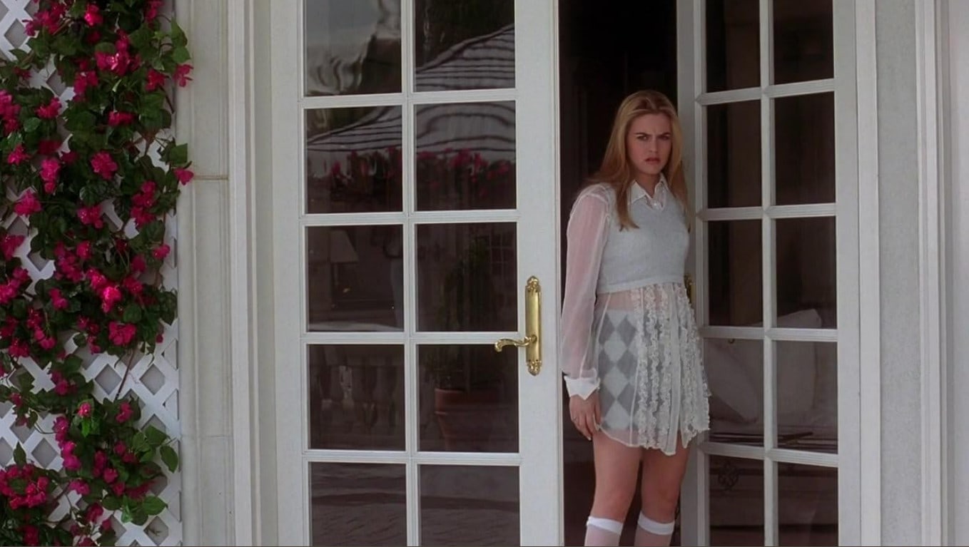 Alicia Silverstone as Cher Horowitz standing at the entrance of her Clueless mansion. Photo credit: IMDB