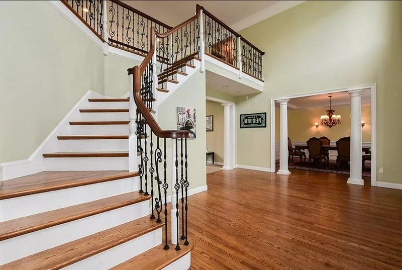 The entrance leads to a stately staircase, with the formal dining room visible on the right. 