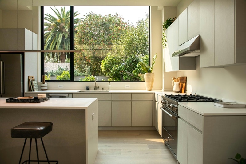 modern, minimalist kitchen with picture windows overlooking lush trees