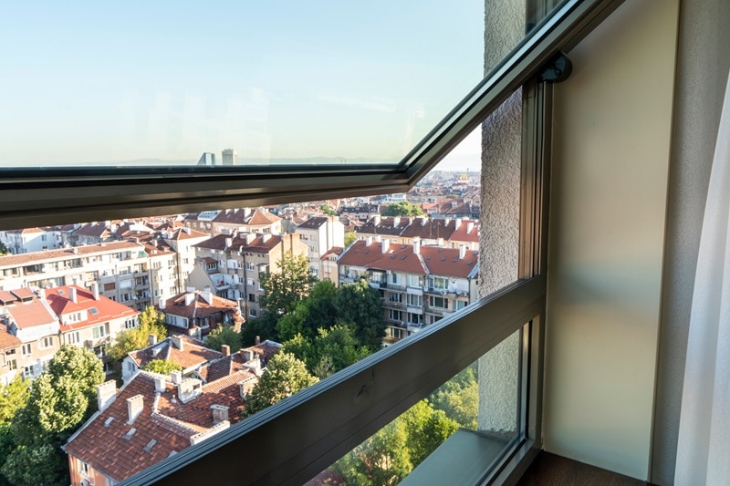 Pivot windows opening up to city views of buildings and trees