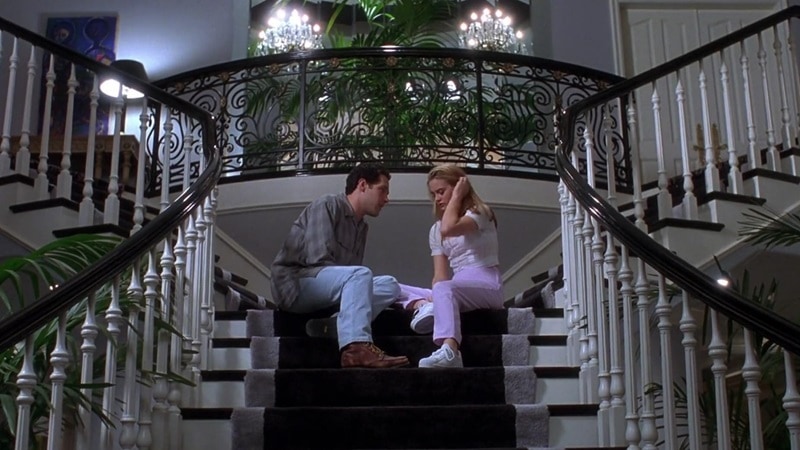 Alicia Silverstone as Cher Horowitz and Paul Rudd as Josh in a Clueless scene taking place at the top of the winding staircase