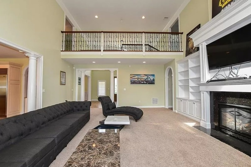 The generously sized living area has double-height ceilings, a fireplace, and built-in shelving.