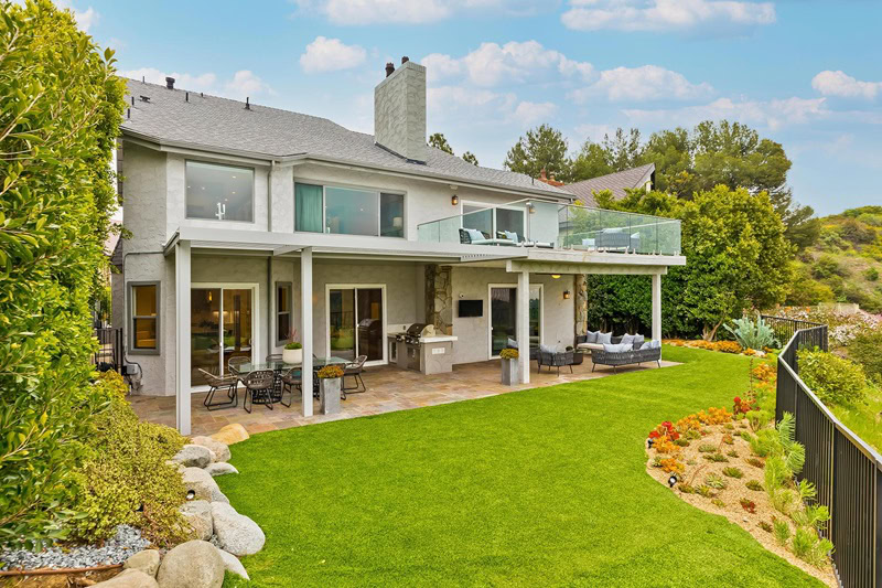 backyard and outdoor kitchen, with two seating areas and a green lawn