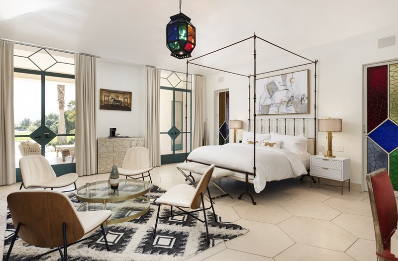 elegant bedroom with a four-poster bed and moroccan style elements like a stained glass door and chandelier