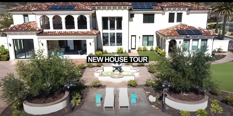 the facade of the house, a two-story mansion with white exteriors and tiled roof, with a water fountain in the courtyard in front