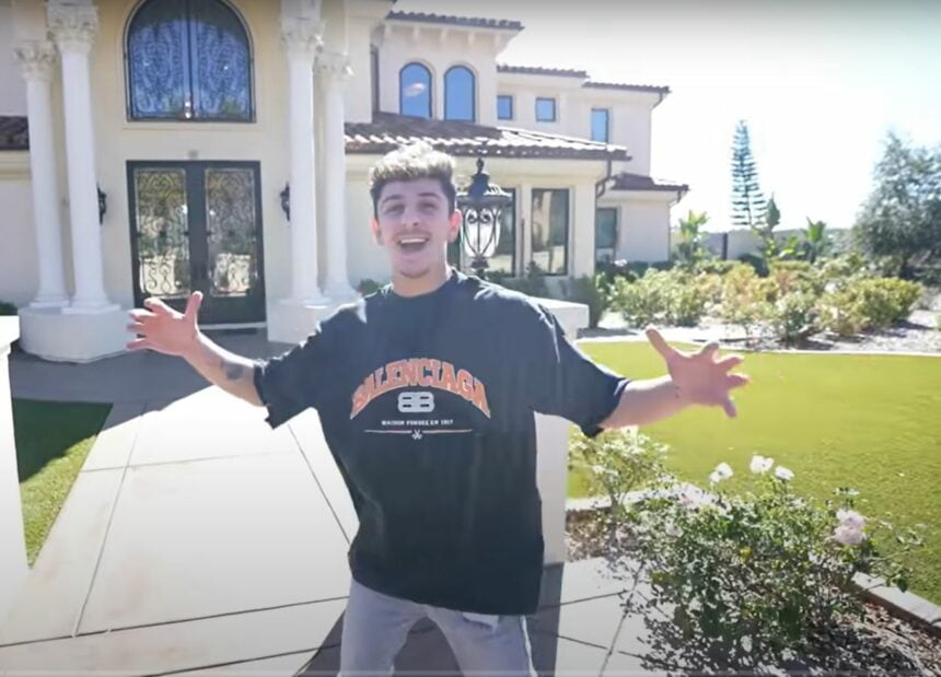 YouTube creator FaZe Rug standing in front of his California mansion, with arms extended, inviting viewers in.