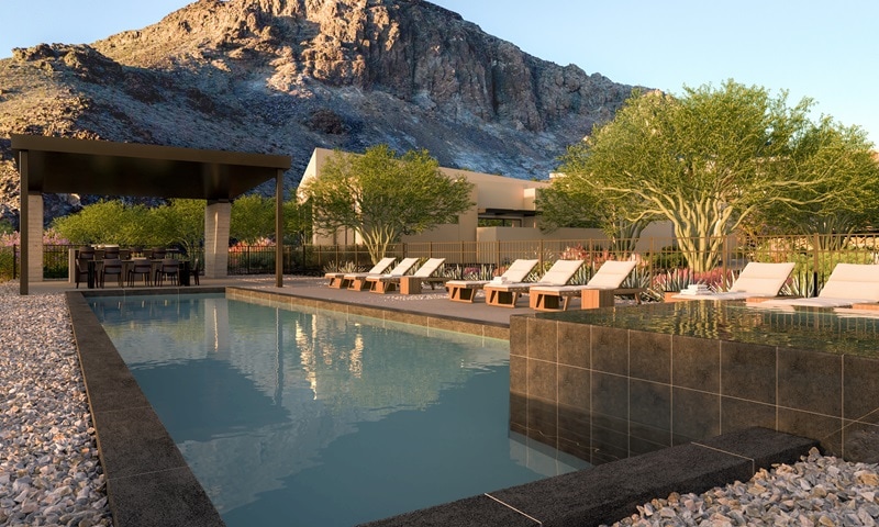 pool with lounging chairs on the side and covered al-fresco dining, with the mountain in the background.