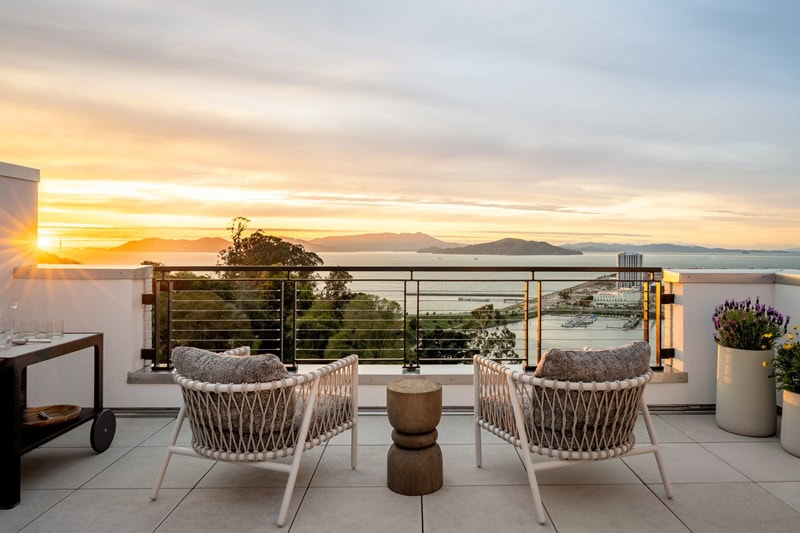 two chairs on a terrace overlooking water views at sunset