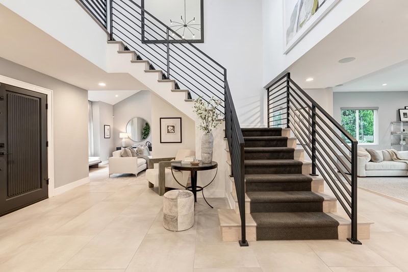 modern interiors with warm beige colors, anchored by a staircase with black railings and a dark rug