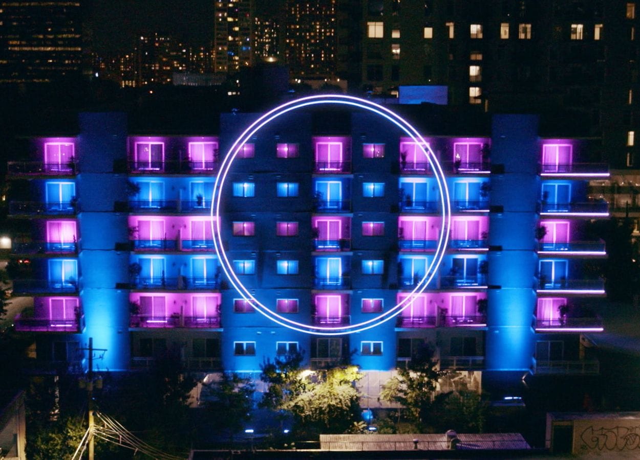 The new apartment building from The Circle, a 6-story residential building with blue and pink lights and a large circle on the facade.