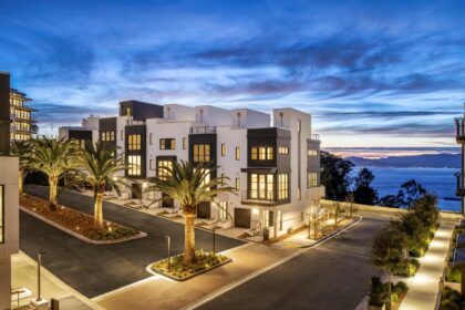 Modern two-story townhomes on Yerba Buena Island, with white and black exteriors, seen at twilight.