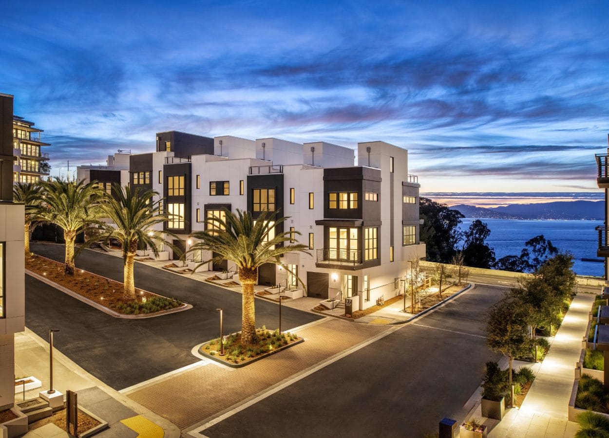 Modern two-story townhomes on Yerba Buena Island, with white and black exteriors, seen at twilight.