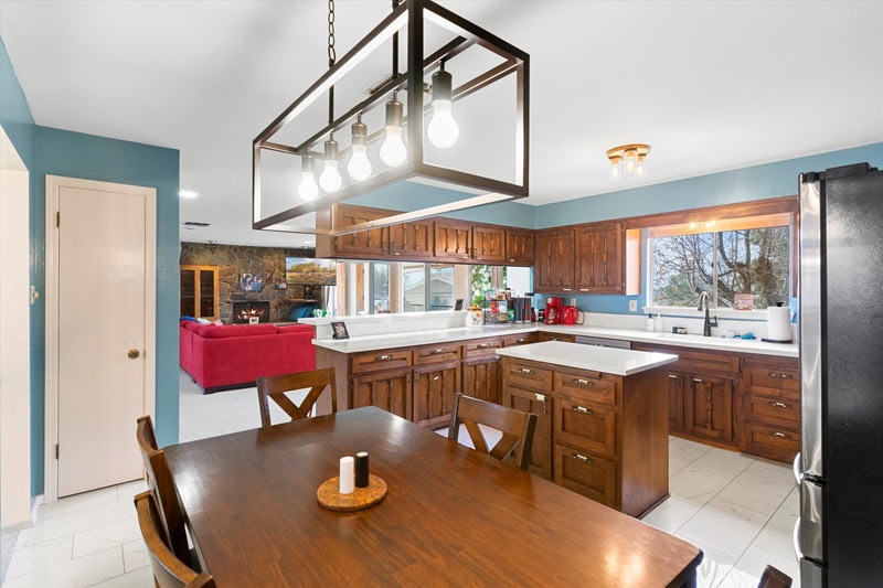 dark wood kitchen with lots of cabinets and a table with chairs set underneath a farmhouse-style lighting fixture.