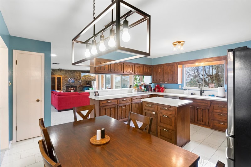 dark wood kitchen with lots of cabinets and a table with chairs set underneath a farmhouse-style lighting fixture. 