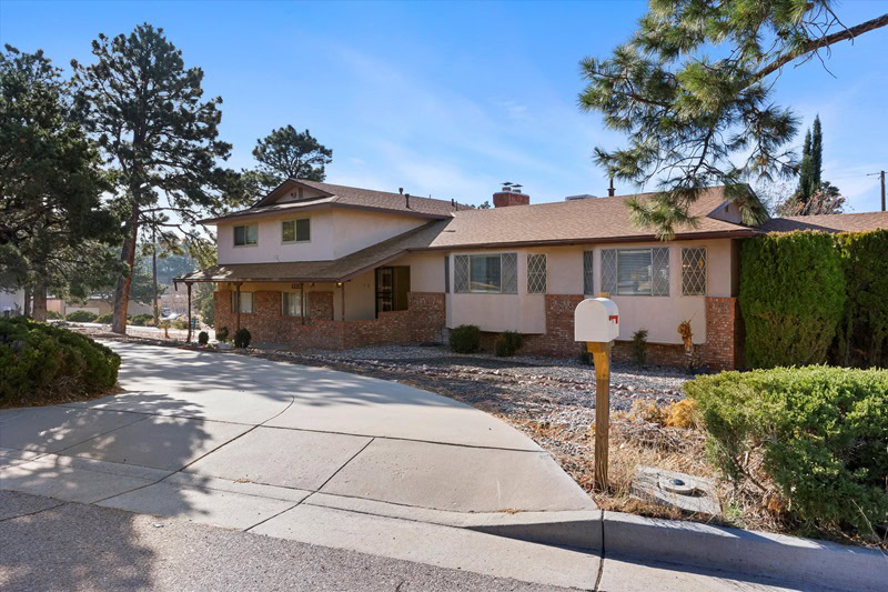 exterior of a two-story house in Albuquerque with faded pink exteriors and a driveway with a white mailbox.