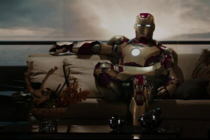 Tony Stark wearing his Iron Man suit and lounging comfortably on the sofa of his house.