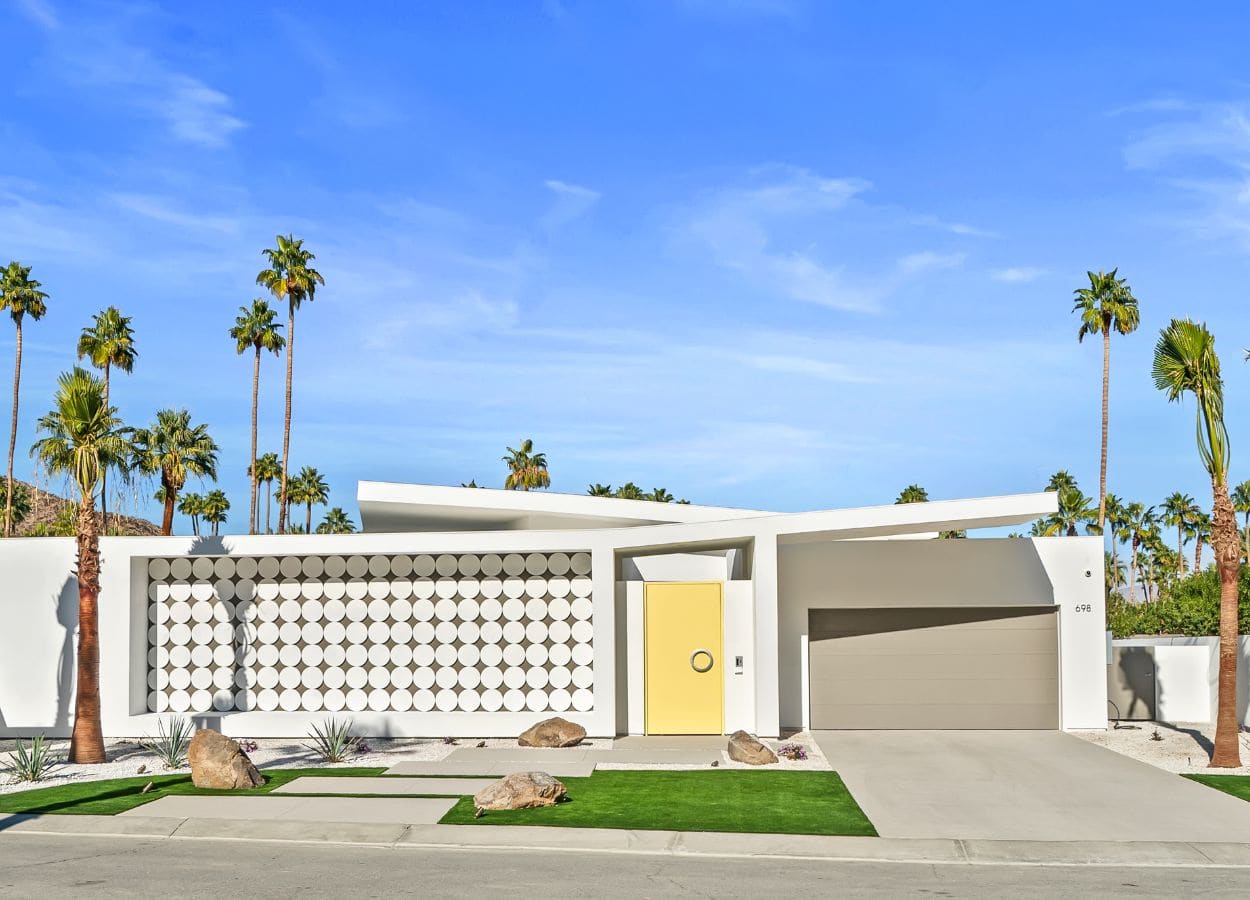 Architecturally distinct house in Palm Springs with a curvilinear design and a bright, yellow door.