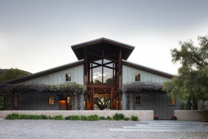 A rustic modern house built like a converted barn. Seen at twilight.