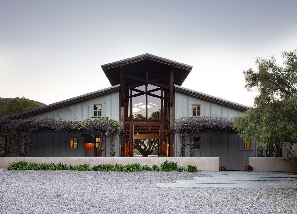 A rustic modern house built like a converted barn. Seen at twilight.