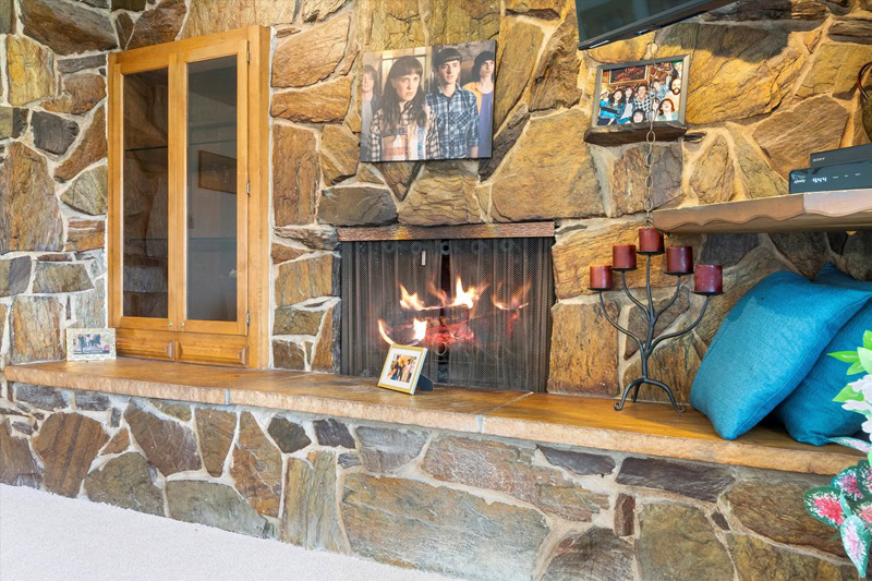 wood-burning fireplace surrounded by stone with a fake window to the side and lots of Stranger Things memorabilia peppered around it. 