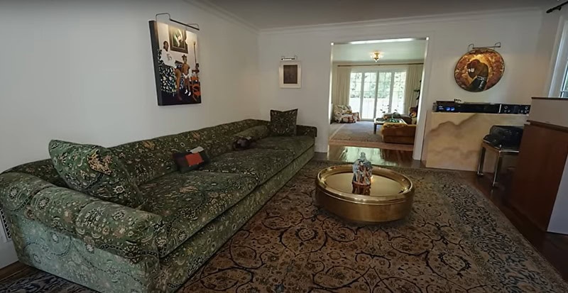 inside Benny Blanco's "listening room", anchored by a large green velvet couch with floral pattens, sitting across the room from two vintage speakers.